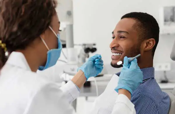 Young african guy smiling to his female dentist during crown consultation at Grins & Giggles Family Dentistry in Spokane Valley, WA