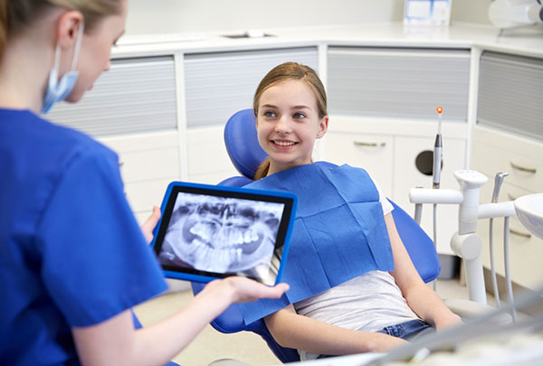  A smiling child looking at X-rays from Grins & Giggles Family Dentistry in Spokane Valley, WA