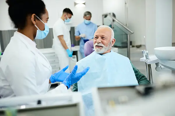 Older patient sitting in dental chair calmly discussing his oral health with his female dentist at Grins & Giggles Family Dentistry in Spokane Valley, WA