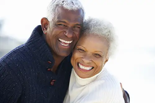 Older man and woman hugging and smiling with their new dentures by Grins & Giggles Family Dentistry in Spokane Valley, WA